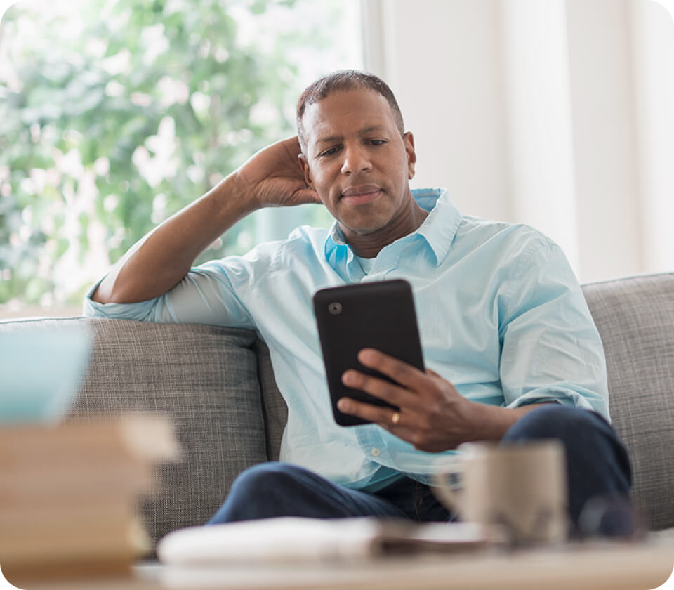 A person sitting on a couch looking at a tablet